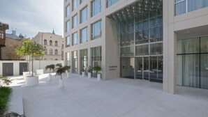 Un bâtiment moderne doté de grandes fenêtres et d’une cour intérieure agrémentée de plantes en pot.