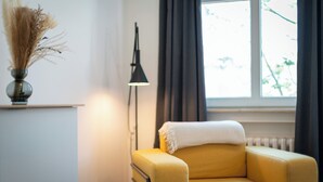 A room with a yellow armchair, a lamp, and a window with curtains. - nestup Hildesheim Zentral (Hildesheim)