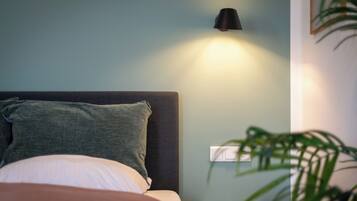 A bedroom with a bed, a bedside lamp, a nightstand, and a wall switch.
