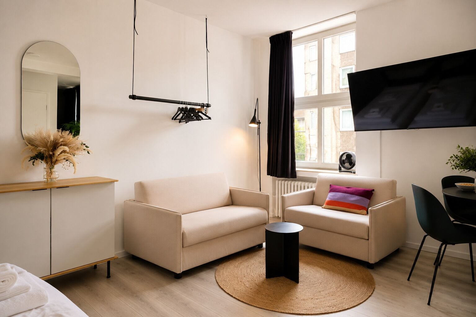 A modern living room with a sofa, a coffee table, a TV, and a dining area.