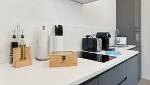Una cocina moderna con encimera blanca, electrodomésticos de acero inoxidable y horno empotrado.