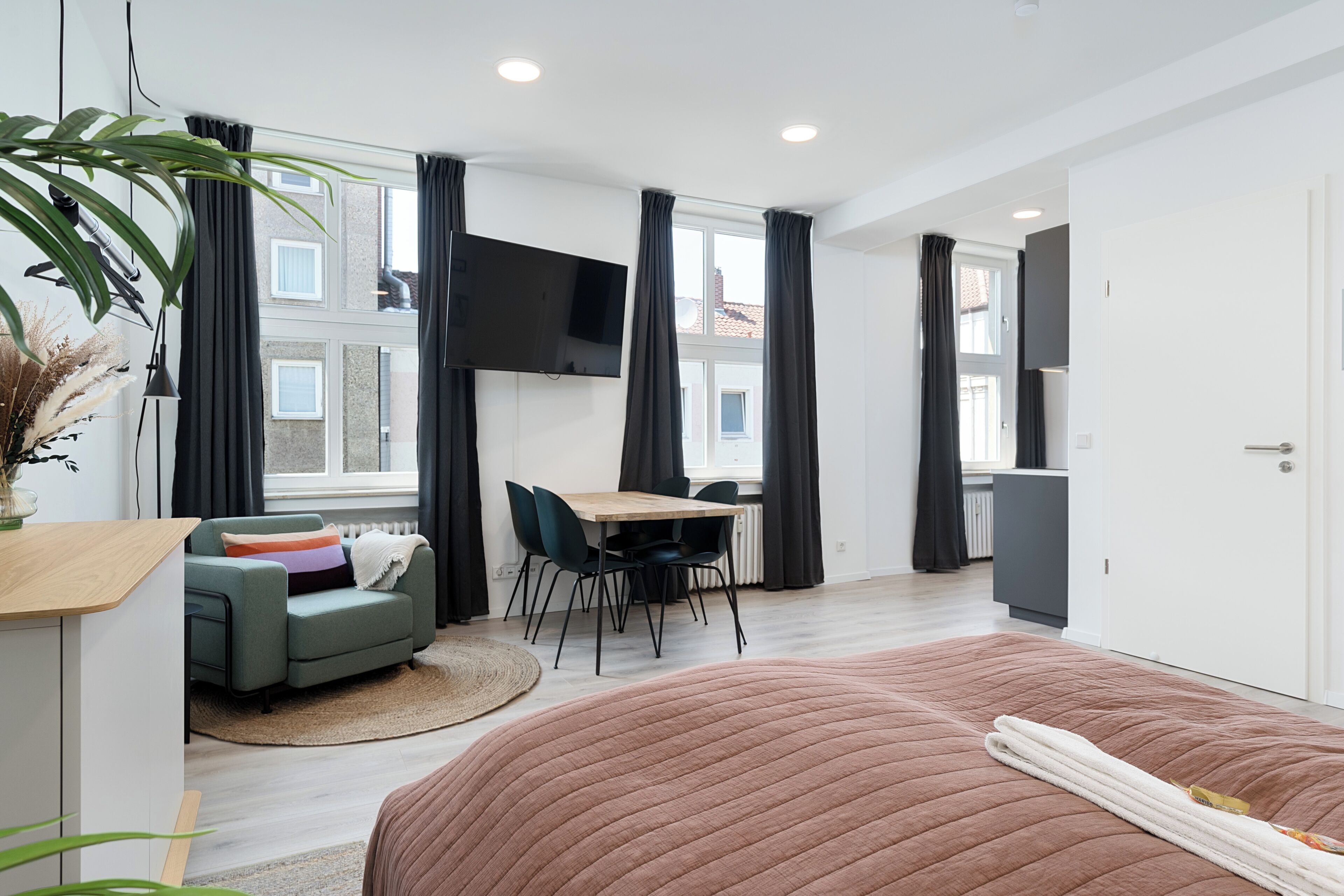 Et moderne hotelværelse med en stor seng, et skrivebord, en sofa og et fjernsyn.