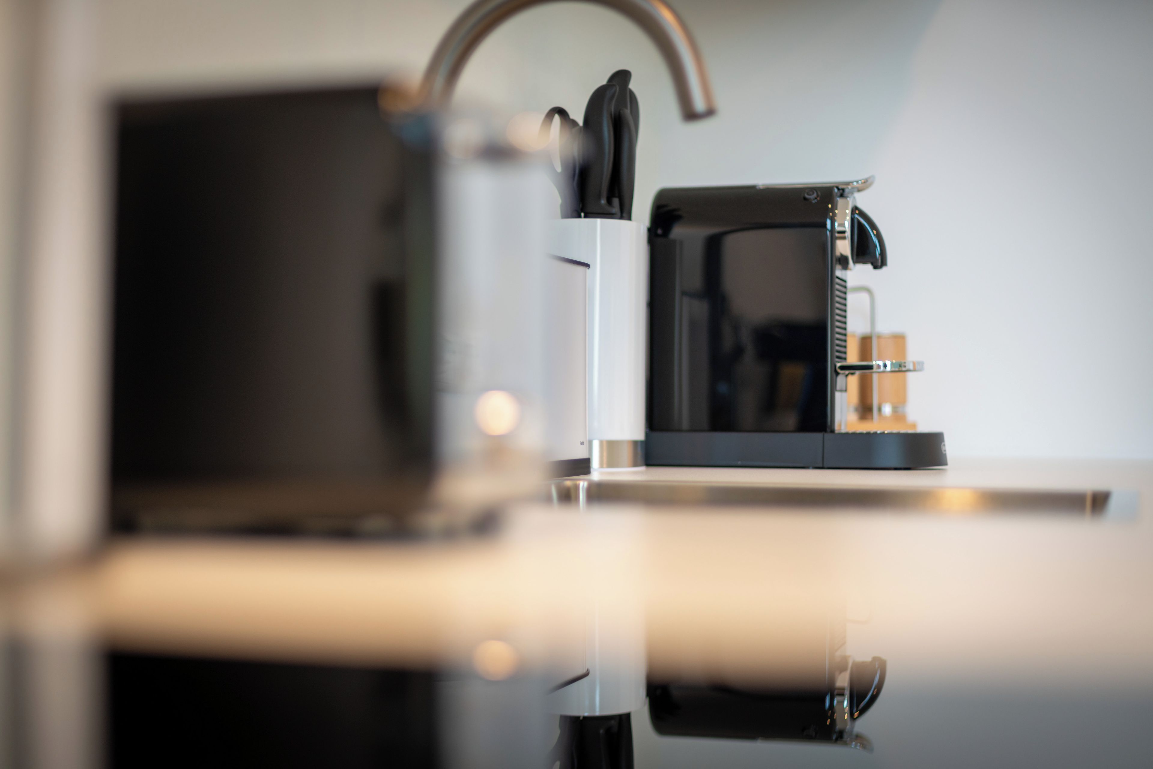 A coffee machine on a countertop with a reflective surface.