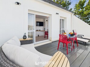 A modern outdoor living area with a sofa, dining table, and chairs.