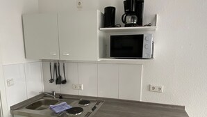 Una cocina compacta con microondas integrado, cafetera y lavavajillas.