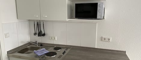A compact kitchen with a built-in microwave, a coffee maker, and a dishwasher.