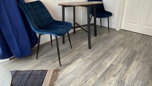 Una habitación con dos sillas azul oscuro, una pequeña mesa redonda y suelo de madera.