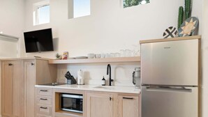 Una cucina moderna con forno integrato, frigorifero in acciaio inossidabile e TV a schermo piatto fissata al muro.