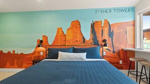 Una camera da letto con un letto, una scrivania e un affresco raffigurante le Fisher Towers.