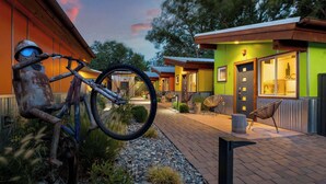Un edificio con facciata verde, una scultura a forma di bicicletta e posti a sedere all'aperto.