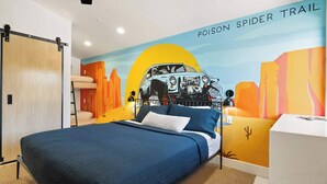Una camera da letto con un letto, una scrivania e un murale raffigurante un'auto e un paesaggio desertico.