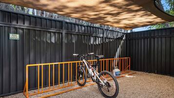 A bike lock and a gas canister near a bike rack under a shaded area.