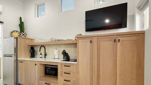 A modern kitchen with wooden cabinets, a built-in oven, a refrigerator, and a flat-screen TV mounted above the countertop.
