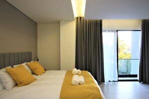 A hotel room with a bed, a headboard, a window with curtains, and a view of greenery outside.