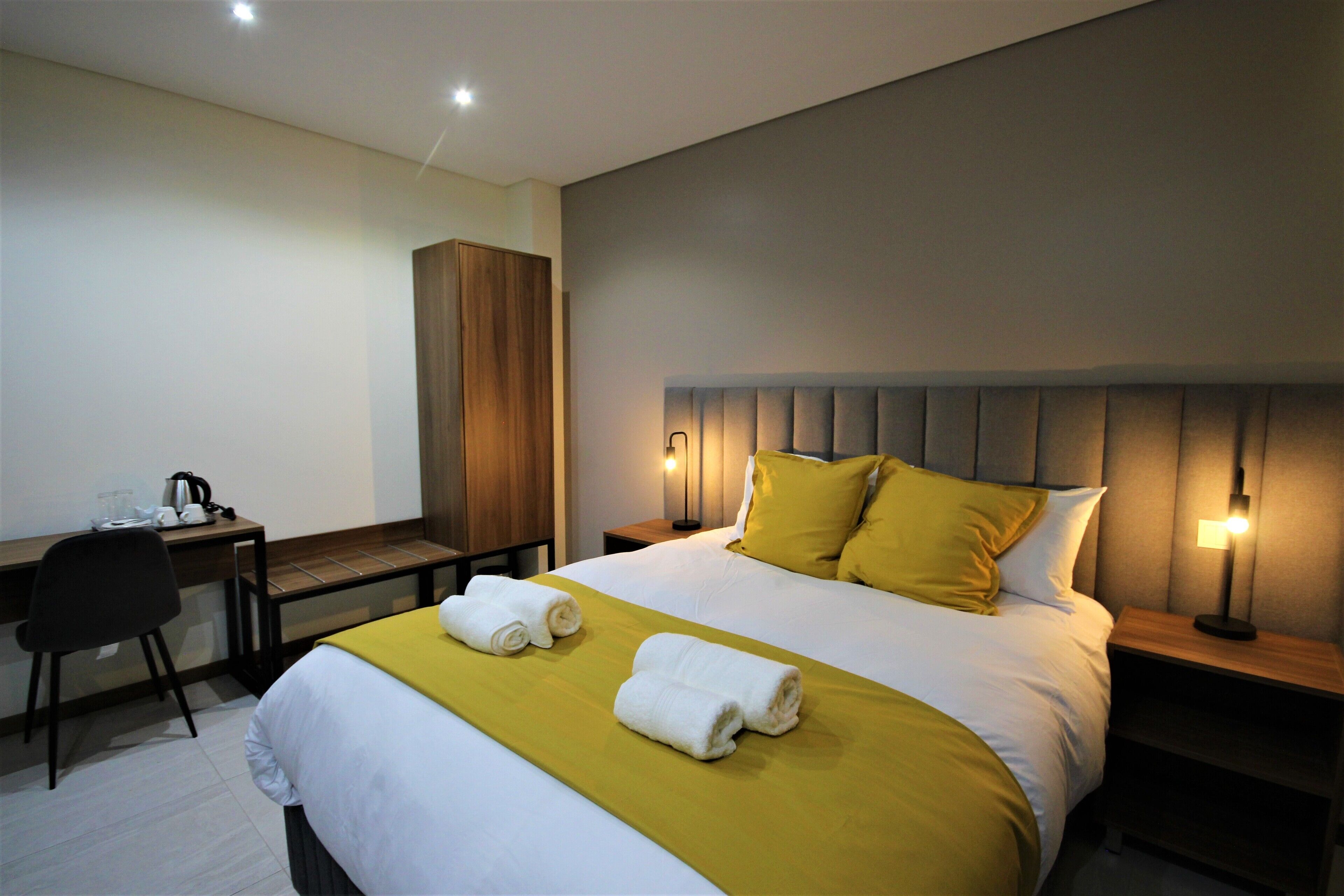 A hotel room with a bed, a desk, and a chair.