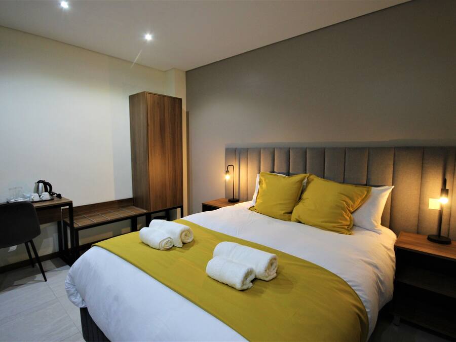 A hotel room with a bed, a desk, and a chair.