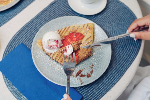 A plate with a waffle, a scoop of ice cream, and a piece of fruit on a blue plate.