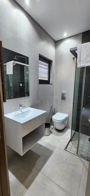 A modern bathroom with a large vanity, a toilet, and a glass shower enclosure.