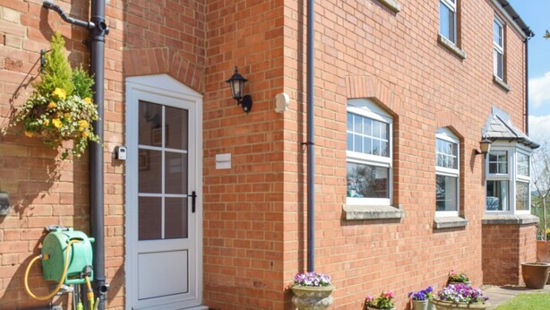 A brick building with a white door, windows, and outdoor flower planters.