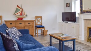 A living room with a blue sofa, a wooden cabinet, a television, and a fireplace.