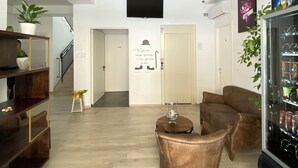 A modern living room with a sofa, a coffee table, and a TV mounted on the wall. There is a staircase leading to another floor, and a door with a sign on it. - bed and book (Rimini)
