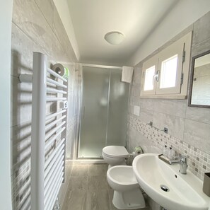 A modern bathroom with a walk-in shower, a toilet, and a sink. - bed and book (Rimini)