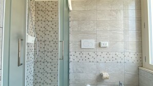 A modern bathroom with a glass shower enclosure, a toilet, and a bidet. - bed and book (Rimini)