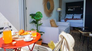 Een kamer met een bed, een ontbijt tafel en een grote plant.