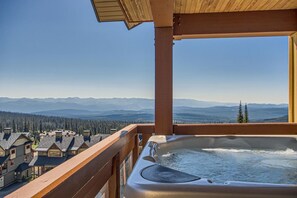 A hot tub on a balcony overlooking a mountainous landscape with multiple houses. - The Crescent by Okanagan Premier (Beaverdell)