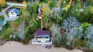 Vista aérea de una casa con terraza, rodeada por un bosque con follaje otoñal.