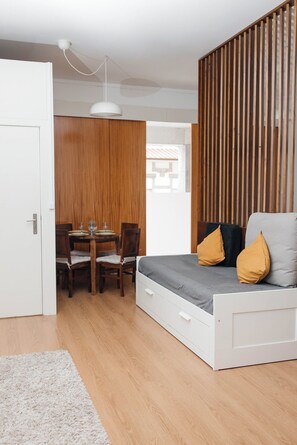 A compact room with a bed, a dining table, and a wooden partition.