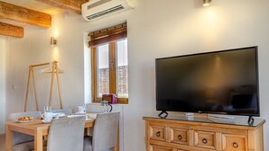 Een eethoek met een houten tafel, stoelen en een televisie op een houten kast.