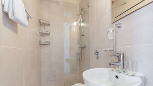 Een moderne badkamer met een witte wasbak, twee douchebakken van glas en een toilet.