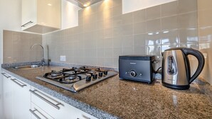 Een keuken met een gasfornuis, een broodrooster en een waterkoker op een granieten aanrecht.