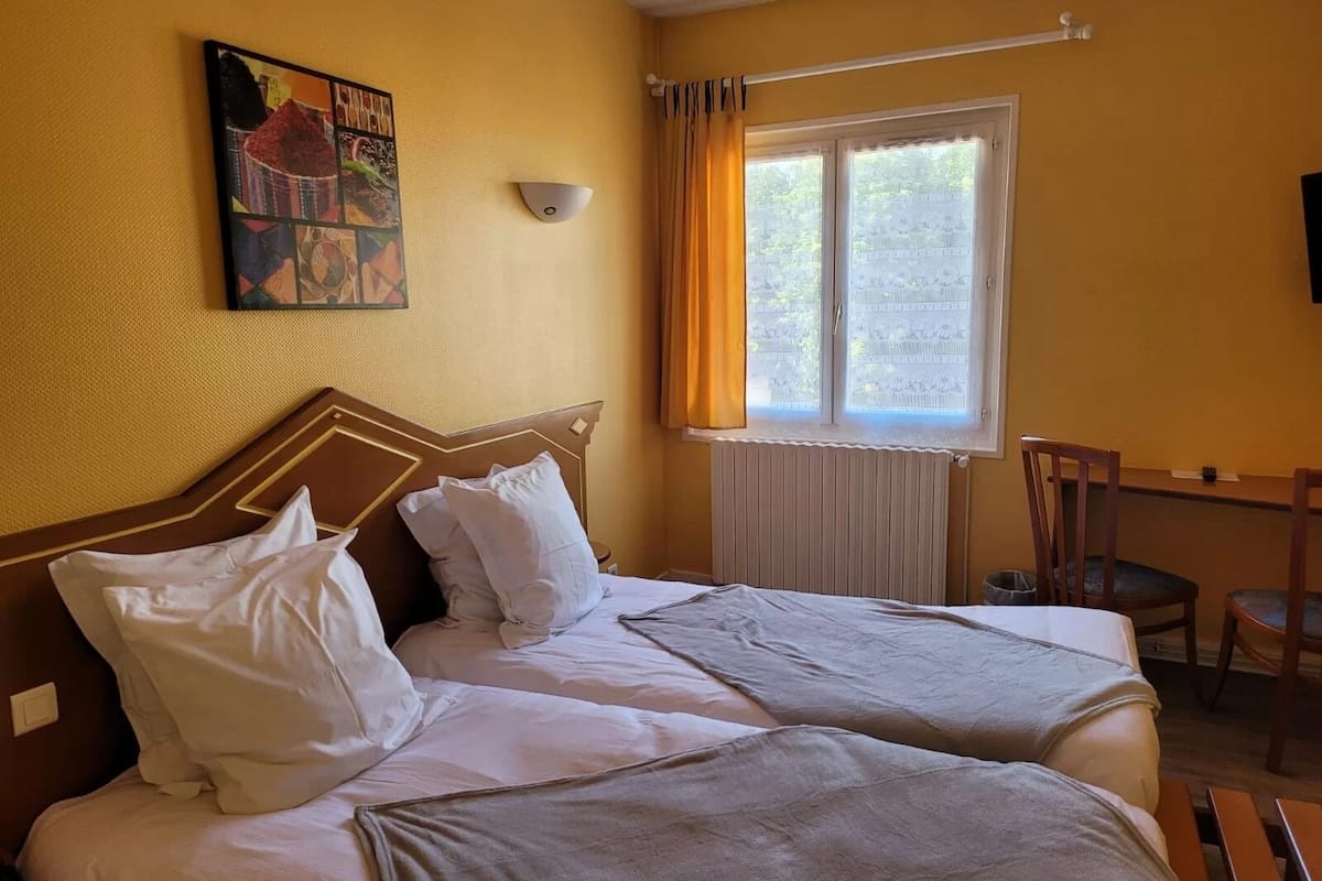 A hotel room with two beds, a desk, and a chair.