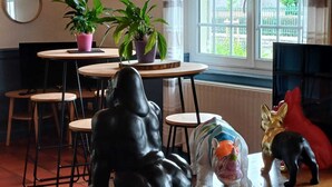 Una habitación con una mesa de madera, sillas, plantas en macetas y una gran escultura de elefante.