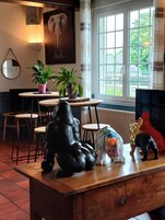 Quarto com uma mesa de madeira, cadeiras, plantas em vasos e uma grande escultura de elefante.