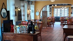 Un restaurante con mesas y sillas de madera, un espejo grande en la pared y vistas a la calle a través de amplias ventanas.
