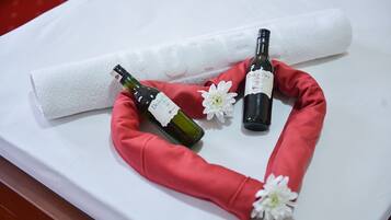 Dos botellas de vino y una toalla enrollada sobre una superficie blanca.