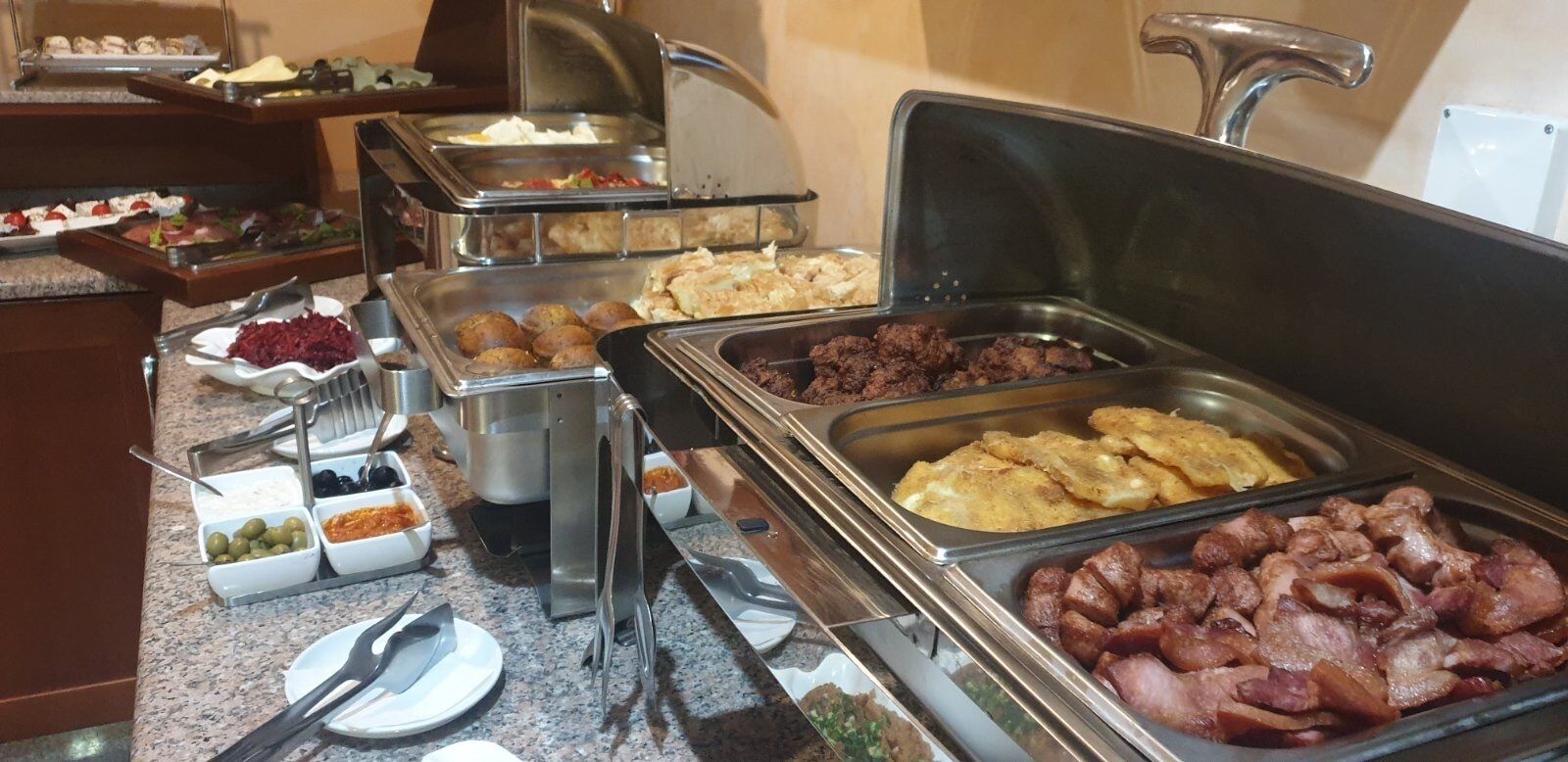 Un bufé con diversos alimentos, incluyendo carnes, verduras y postres.