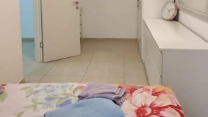 Une chambre à coucher comprenant un lit, une table de chevet, une horloge et une porte donnant sur une autre pièce.