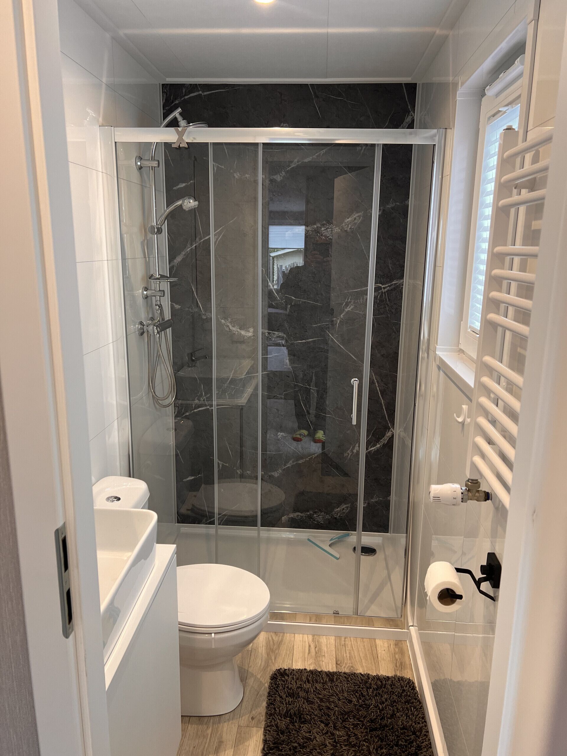 Une salle de bain moderne dotée d’une douche à parois de verre, de toilettes et d’un lavabo.