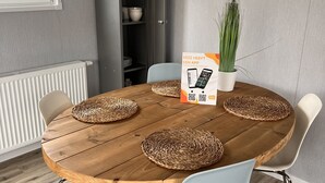 A dining area with a round wooden table, woven placemats, and modern chairs.
