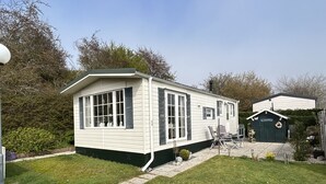 Une petite maison de plain-pied, dotée d’un toit en pente et d’un porche à l’avant.