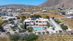Zona residencial com uma casa grande, piscina, painéis solares e vista para uma paisagem montanhosa.