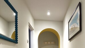 Um corredor com radiador, espelho, cadeira e tapete.