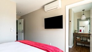 Une chambre à coucher avec un lit, un téléviseur fixé au mur et un appareil de climatisation.