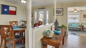 A dining area with wooden chairs and a table, a Texas flag, and a map of the USA on the walls.
