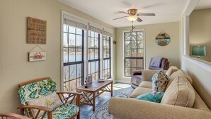 A cozy living room with a large window, a ceiling fan, and a view of a lake.