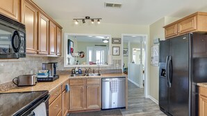 A modern kitchen with wooden cabinets, stainless steel appliances, and a granite countertop.